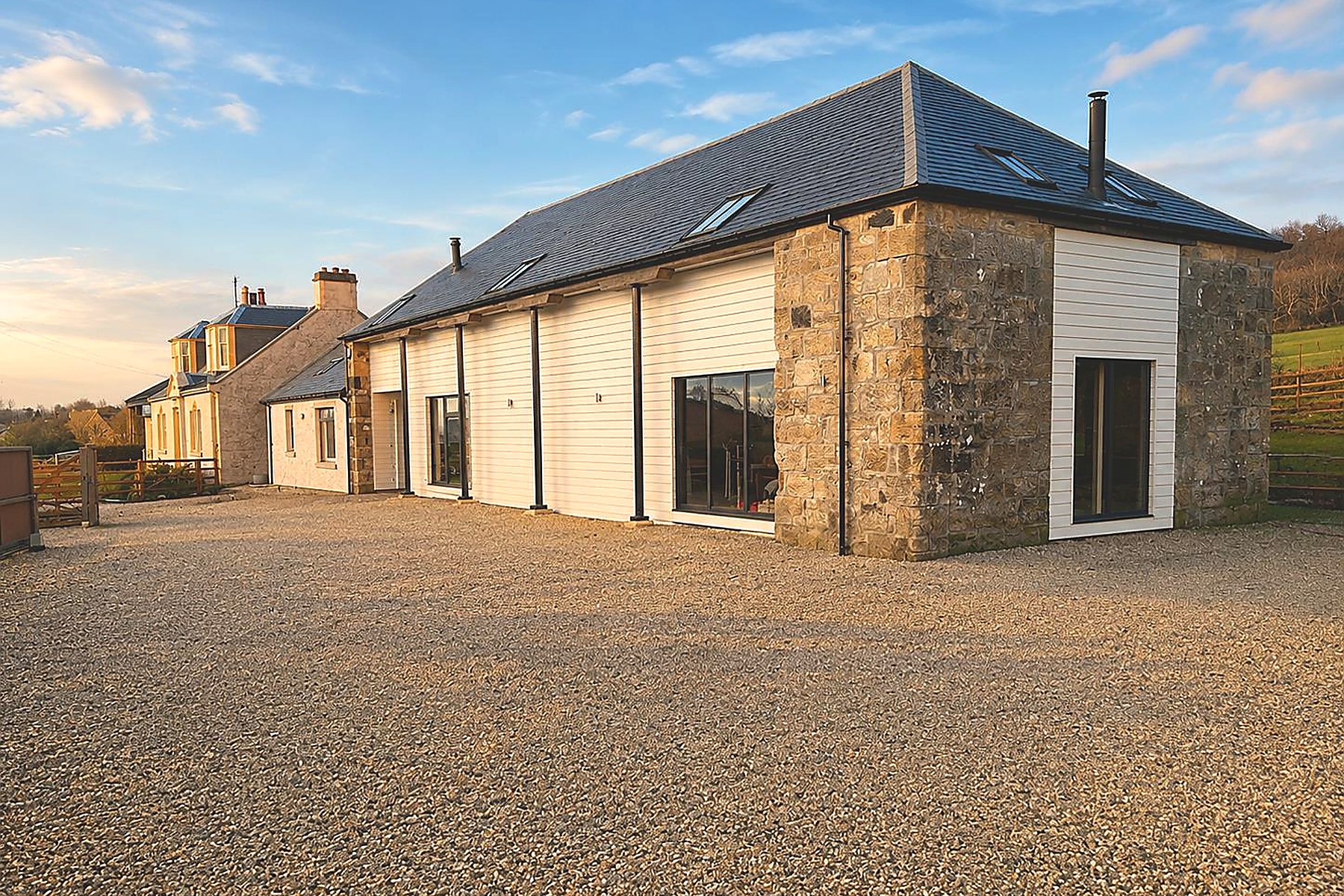 Contemporary stone-and-timber farmhouse conversion in Ayr at golden hour