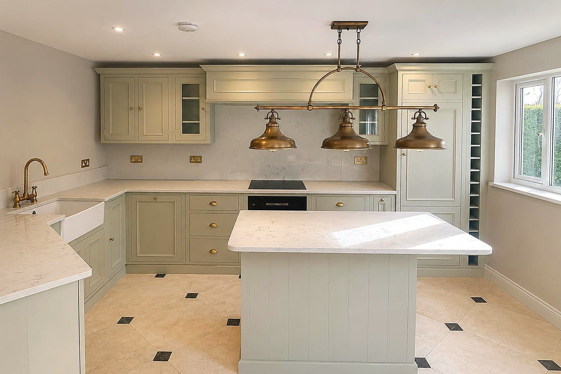Bespoke sage-green kitchen with brass pendants in Fulham townhouse